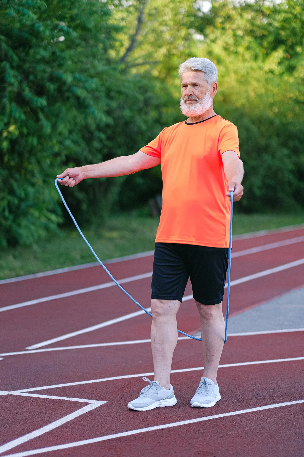 Older athlete practicing jump rope coordination on a running track