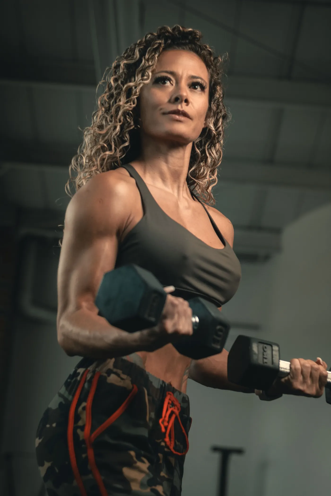 Woman performing a dumbbell strength exercise in a gym