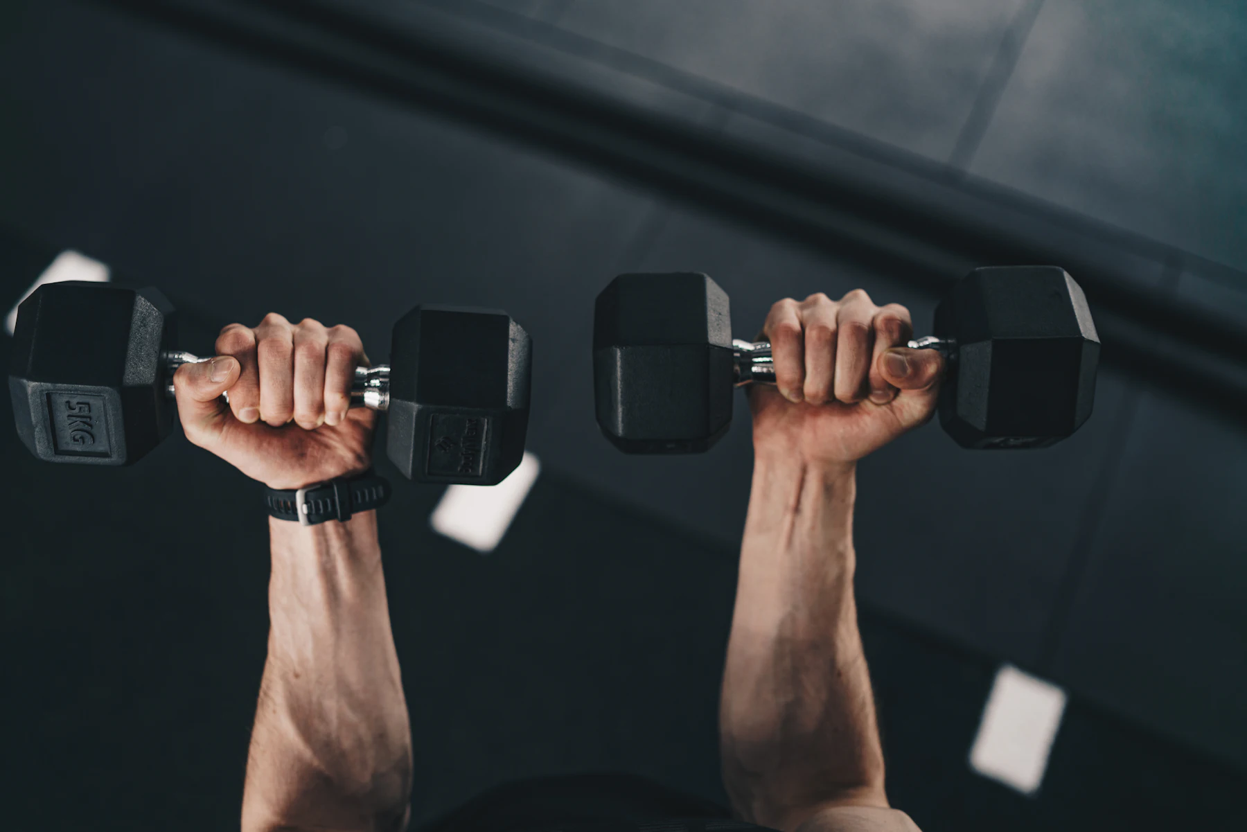 Athlete pressing a pair of dumbbells overhead during a gym session