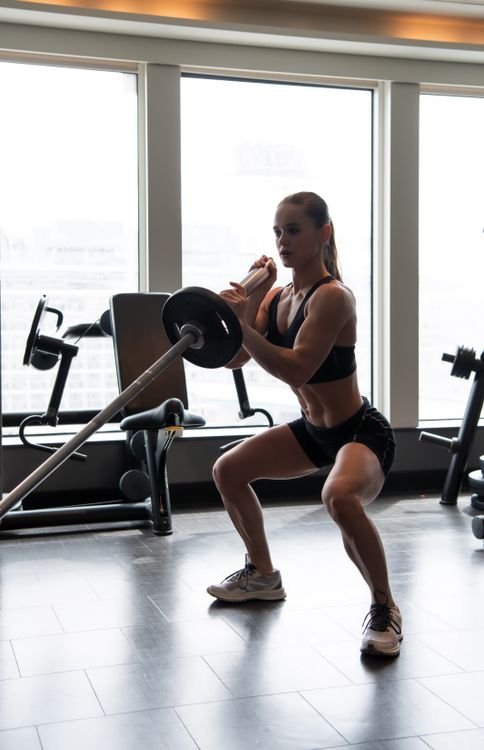 Athlete performing a bilateral barbell squat in a strength gym