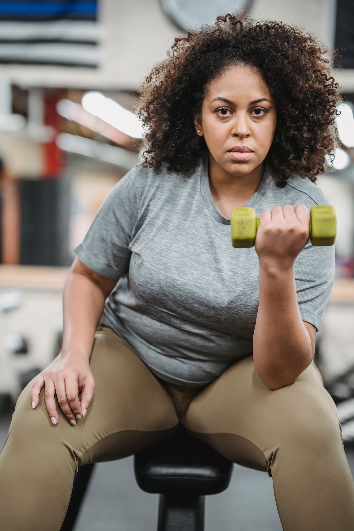 Woman performing a dumbbell curl while seated on a gym bench