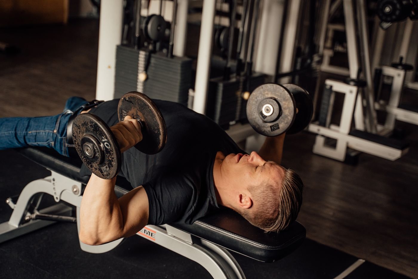 Man pressing dumbbells while lying on a gym bench