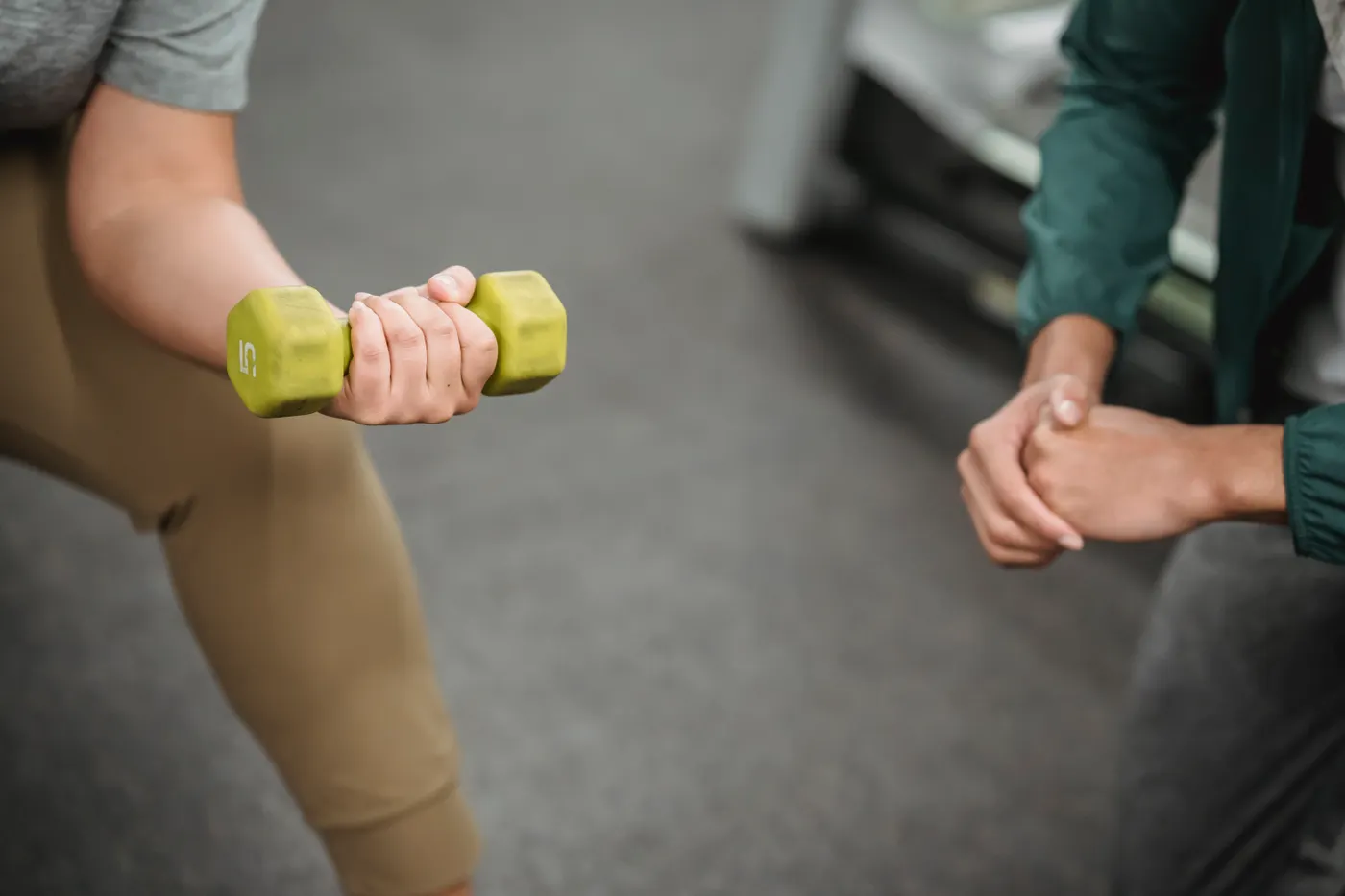 Trainer supervising a woman's dumbbell exercise