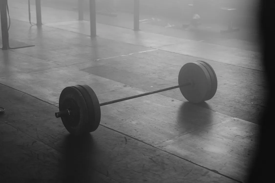 Unloaded barbell resting on the floor of an empty training space