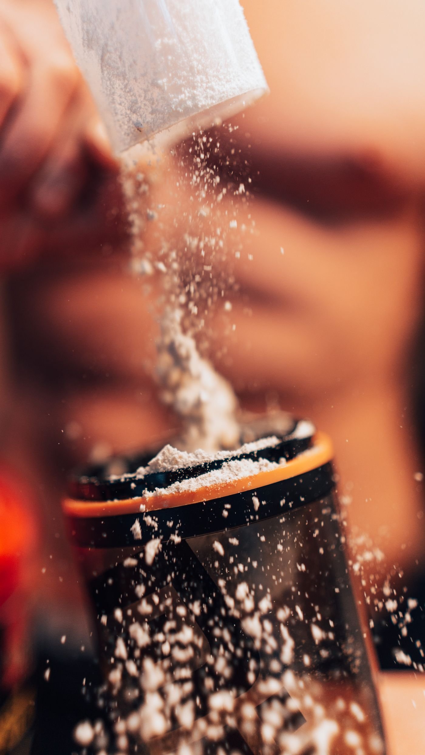 Protein powder being poured into a metal shaker
