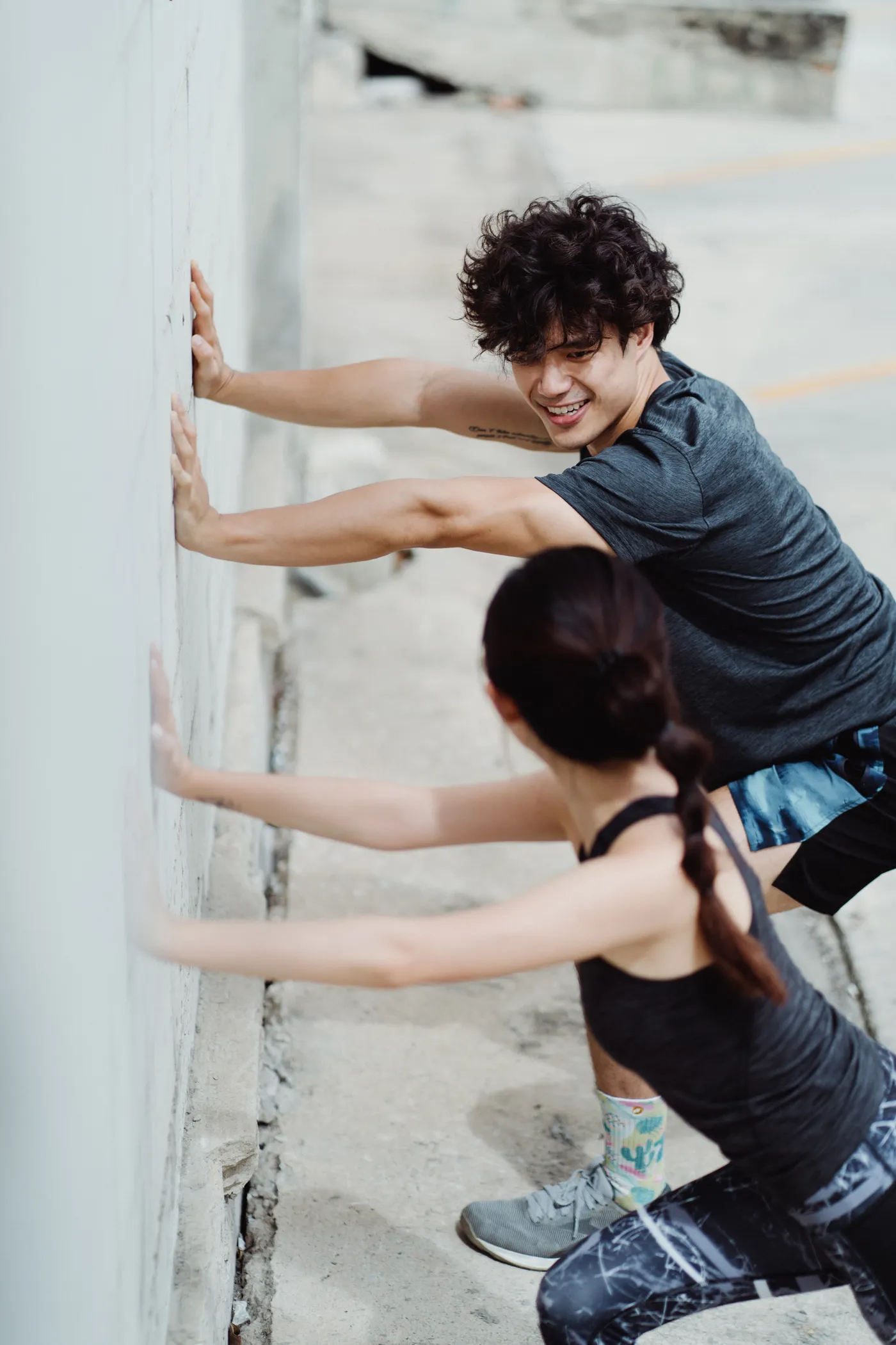 Two athletes stretching beside a wall