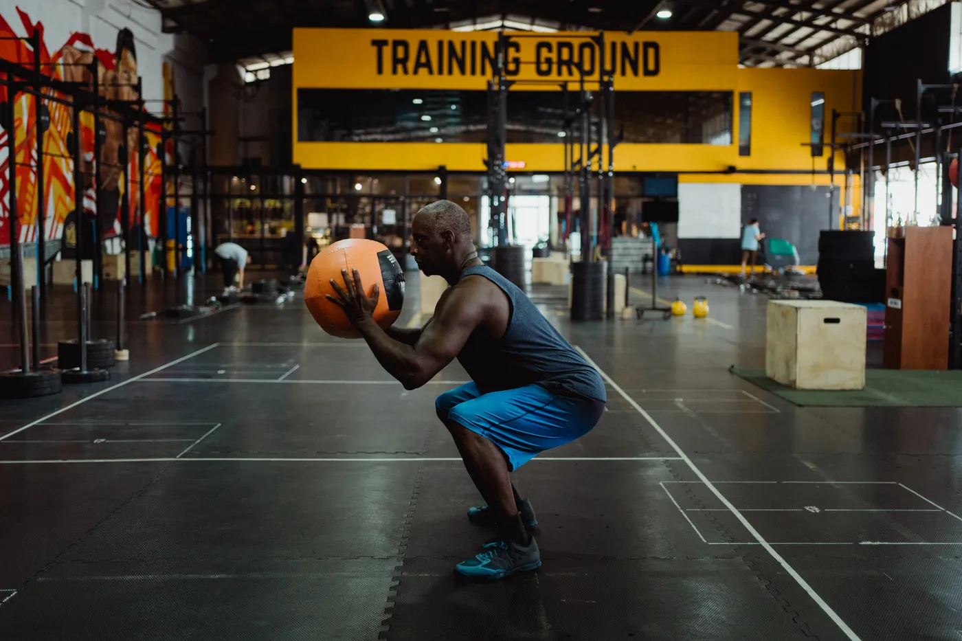 Man squatting with a medicine ball in a gym