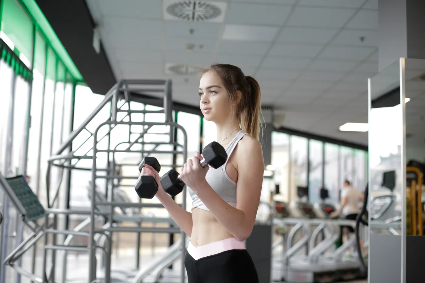 Woman training her arms with dumbbells in a bright gym