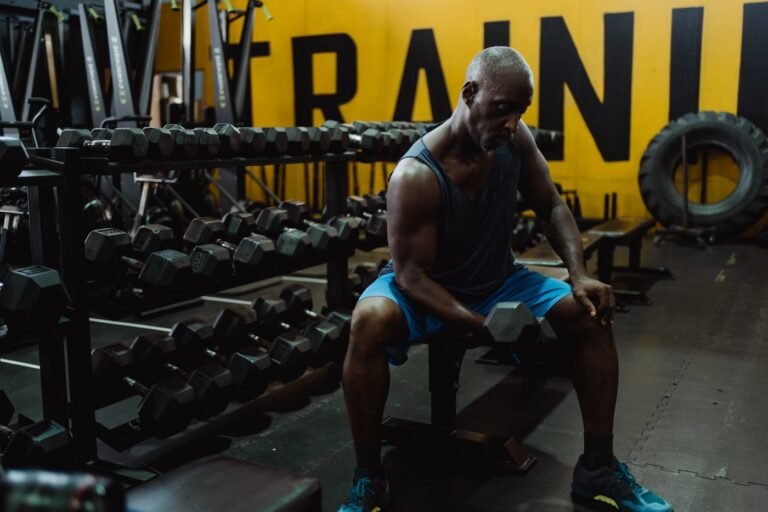 Middle-aged man performing a dumbbell exercise on a weight bench in a gym