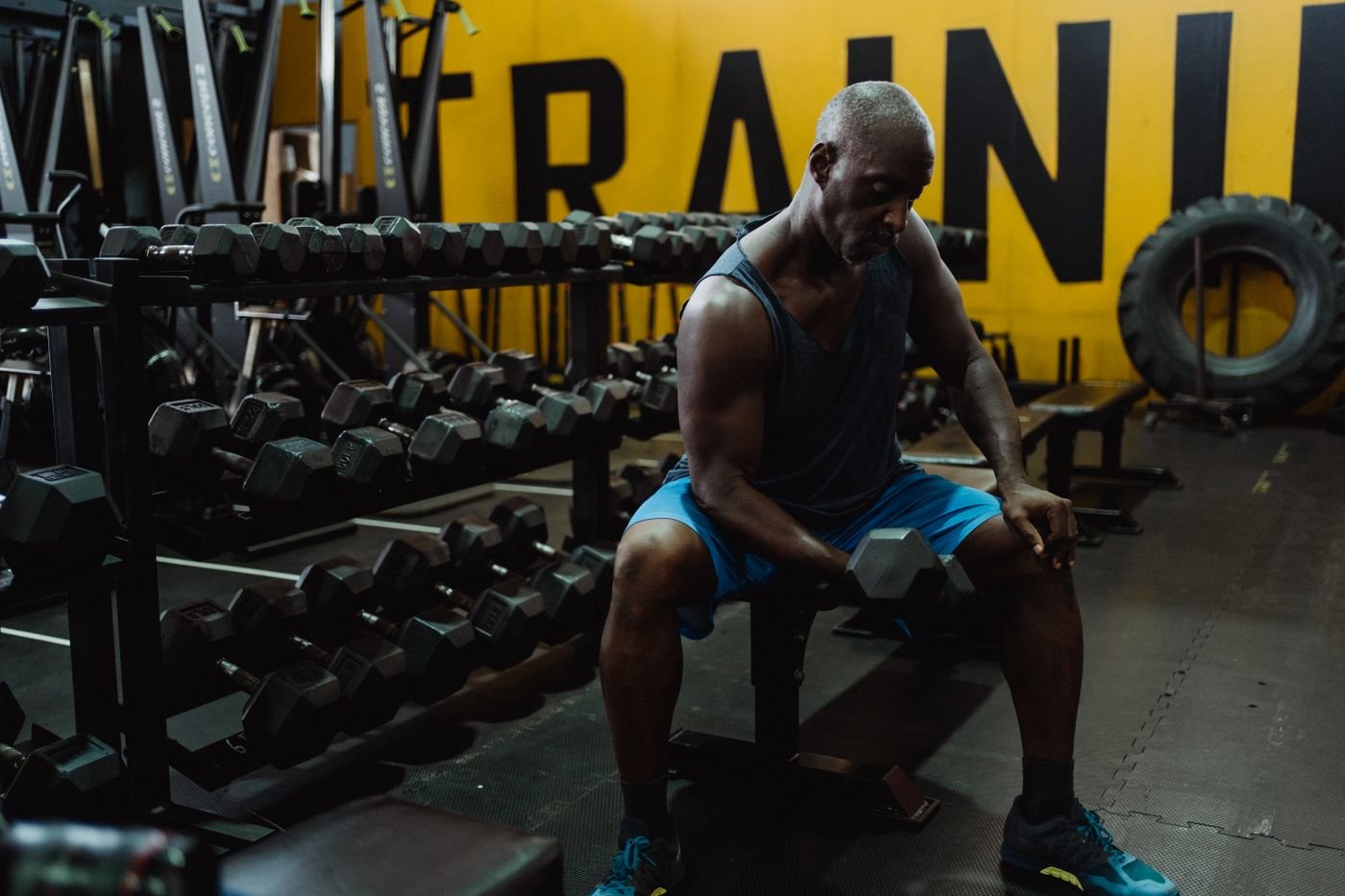 Man training with dumbbells beside a weight bench