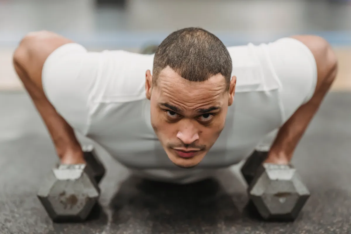 Athlete using dumbbell handles to perform push-ups