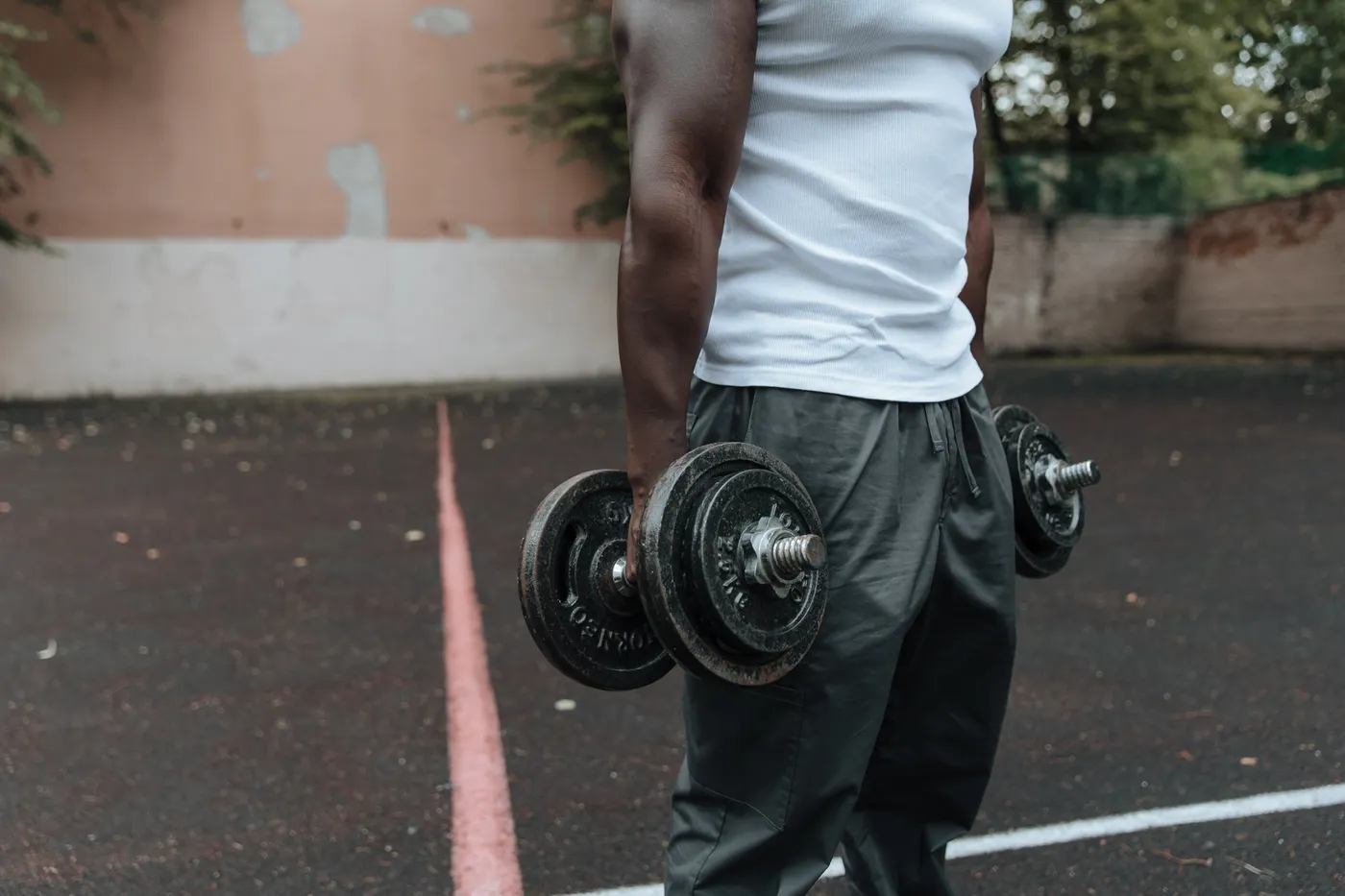 Athlete holding dumbbells beside his body during an outdoor strength session