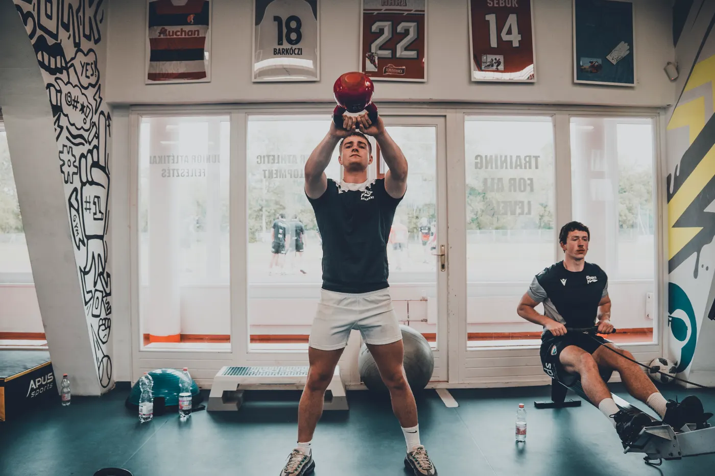 Two athletes practicing kettlebell exercises in a gym