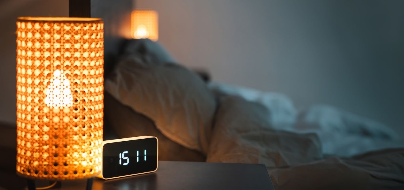 Bedside lamp and alarm clock in a warm bedroom