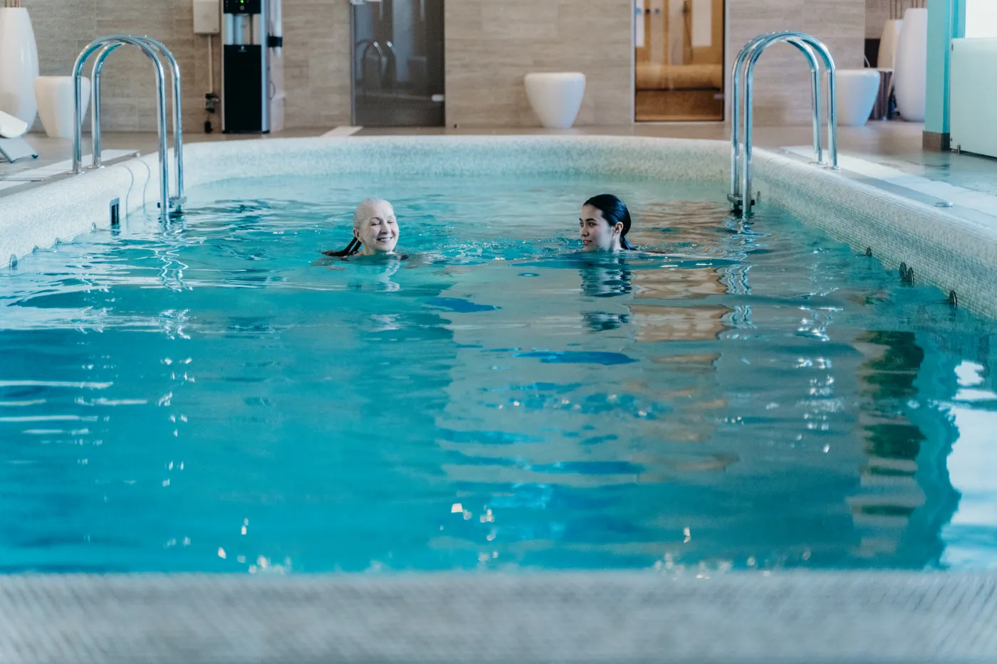Older woman and another adult in an indoor swimming pool