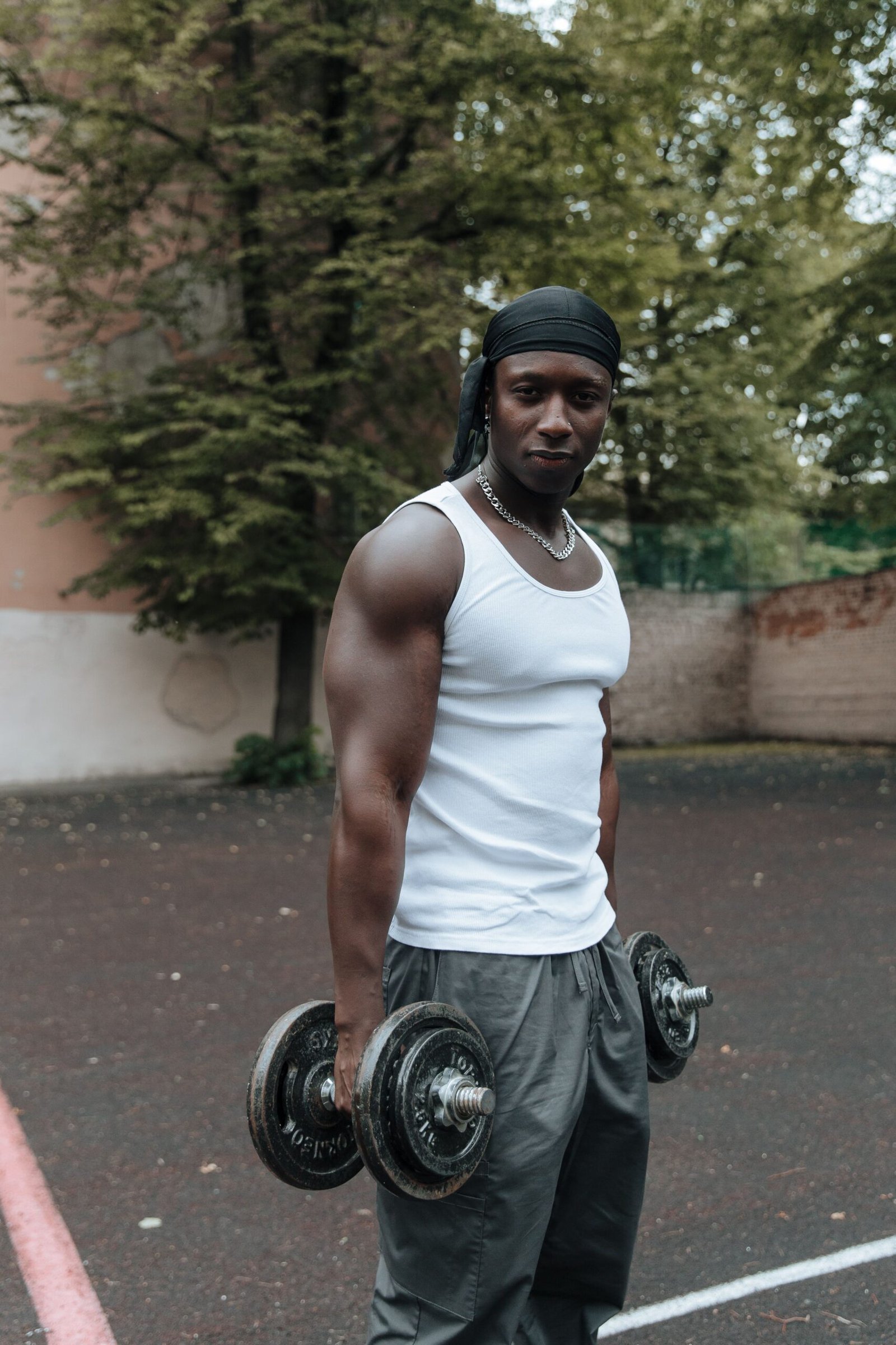 Athlete standing outdoors with dumbbells hanging at both sides