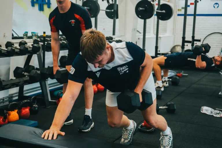 Two men lifting dumbbells during a strength session in a gym