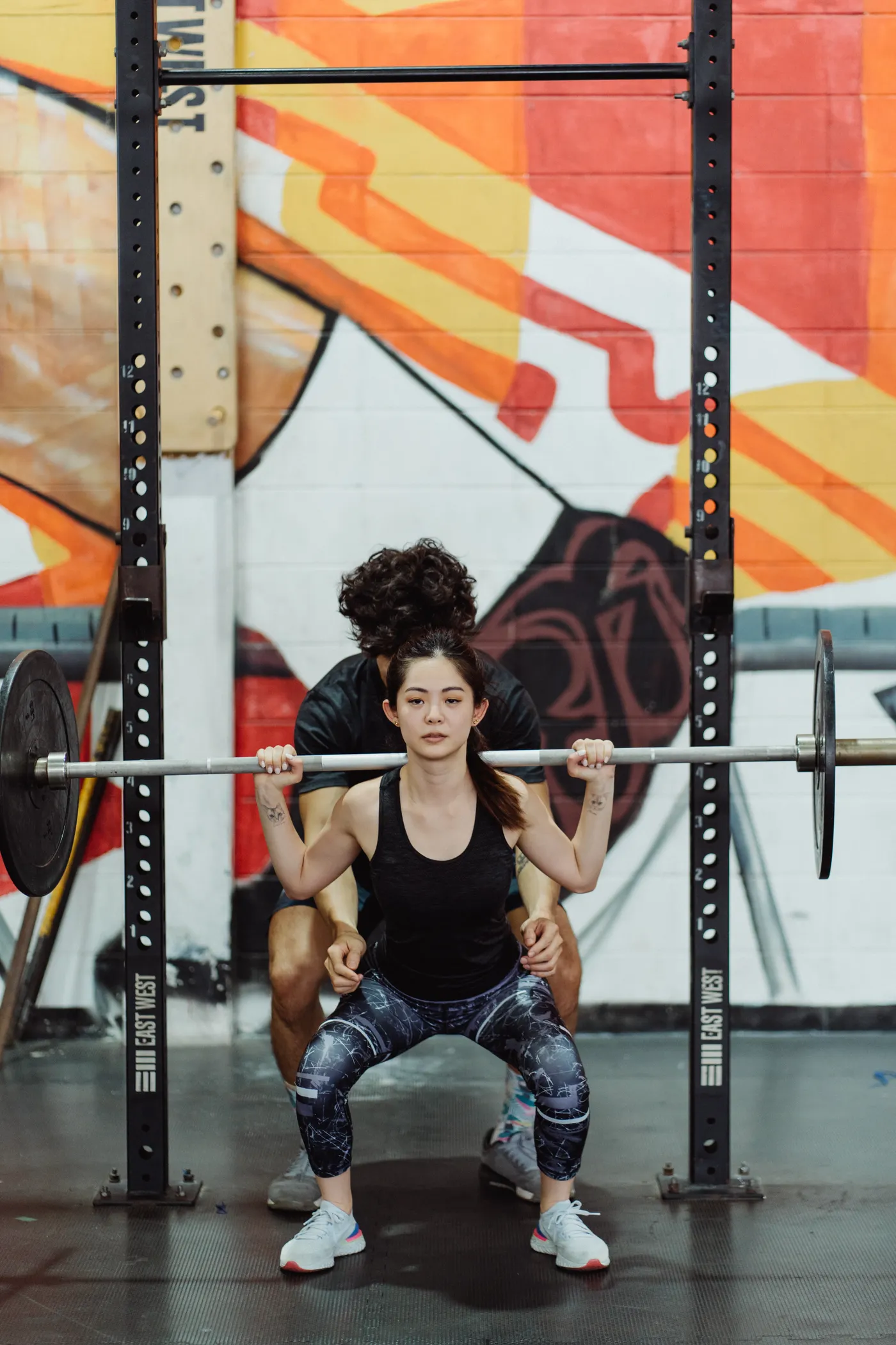 Coach guiding woman during barbell exercise