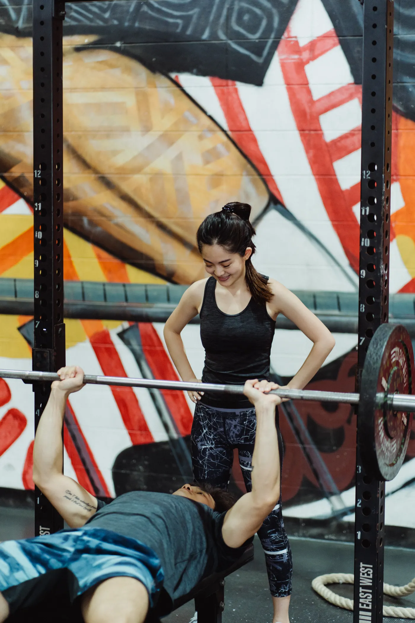 Man performing barbell bench presses with a gym spotter