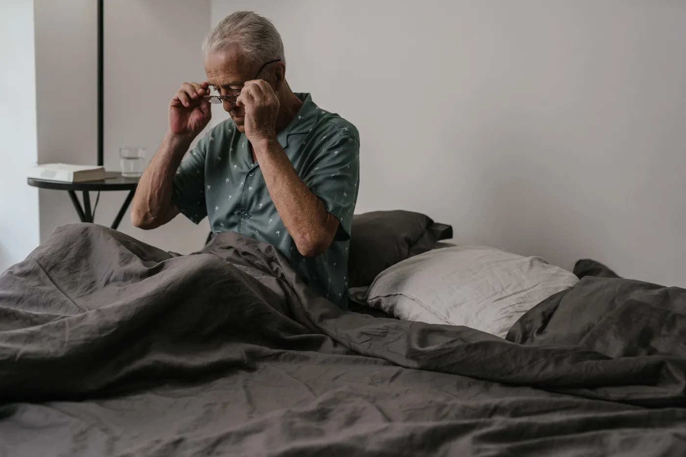 Older man sitting upright in bed at the start of his morning