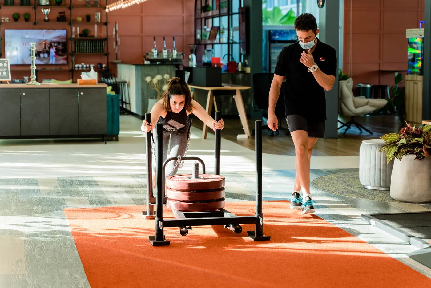 Woman pushing a weighted sled under supervision