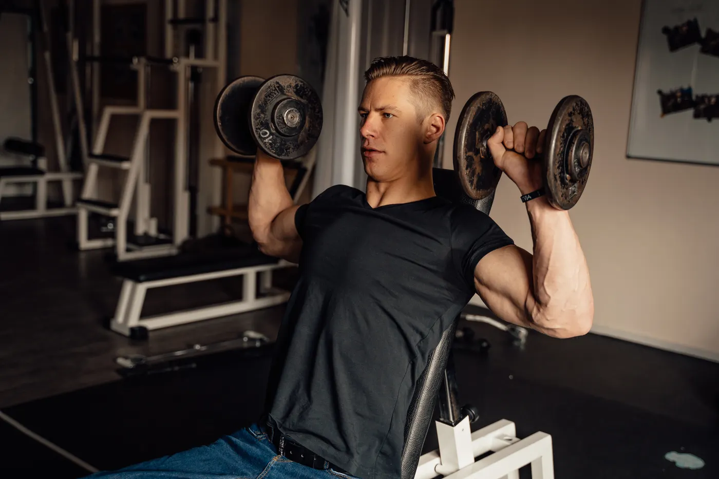 Man performing a dumbbell shoulder press in the gym