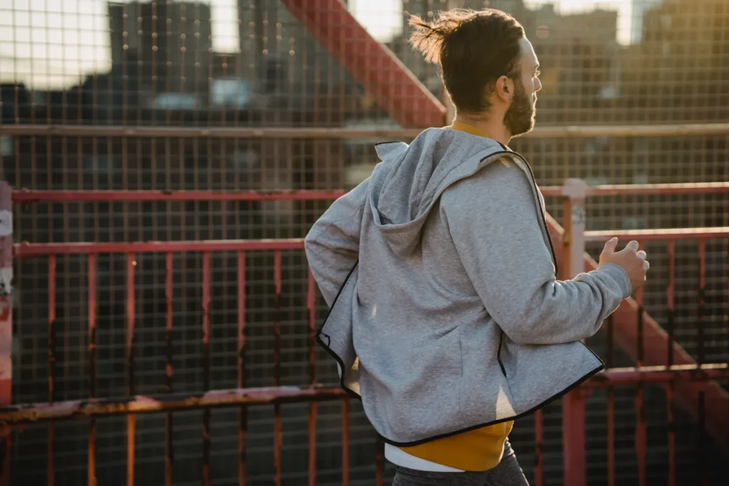 Runner crossing an urban bridge at sunrise during training
