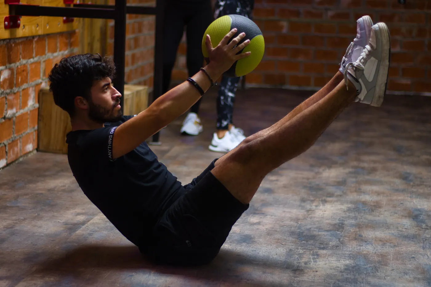 Man performing a core exercise with a medicine ball in a gym