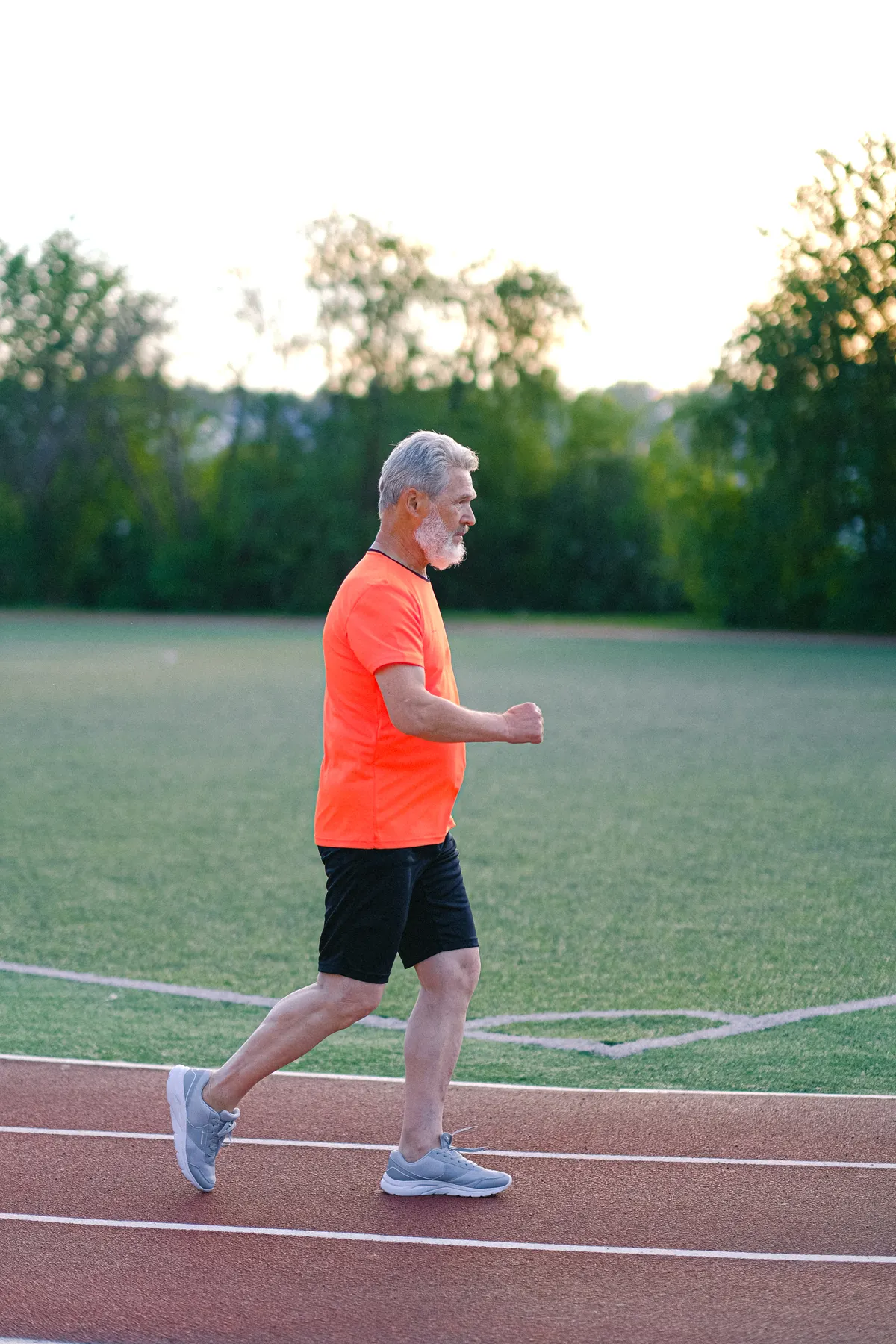 Gray-haired runner practicing steady running on a stadium track