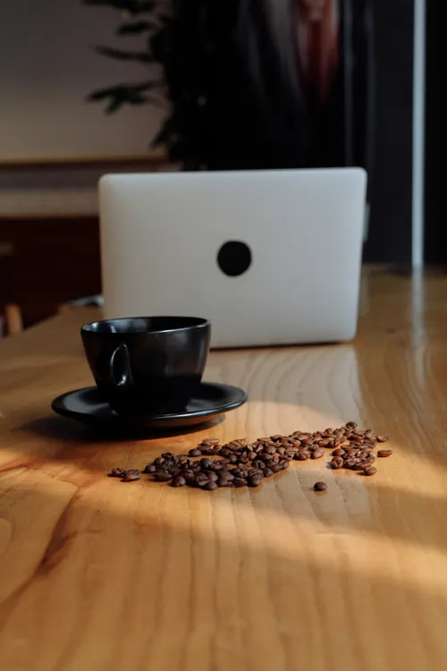 Coffee beside a laptop representing a consistent caffeine routine