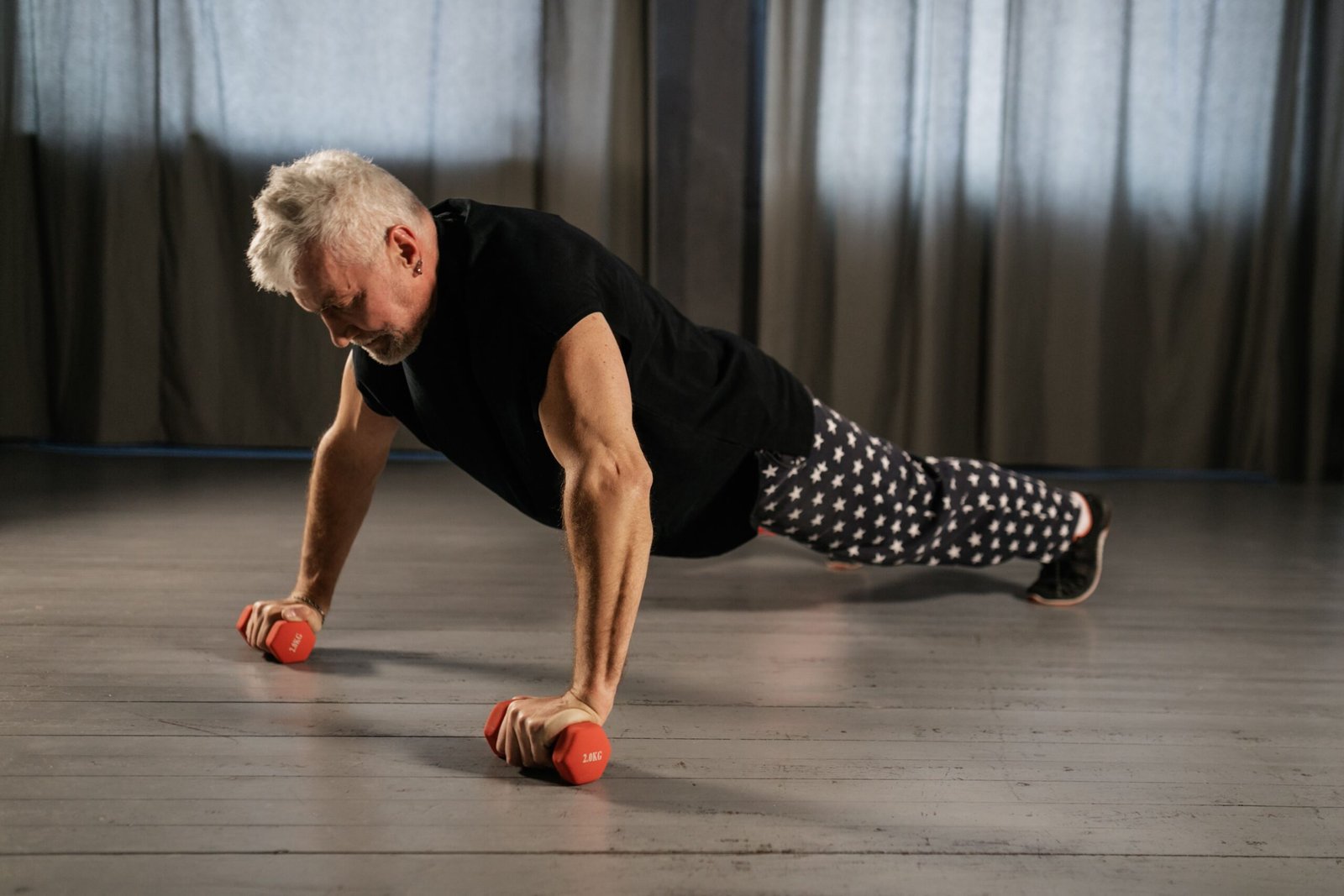 Older man doing a controlled push-up using dumbbells for support