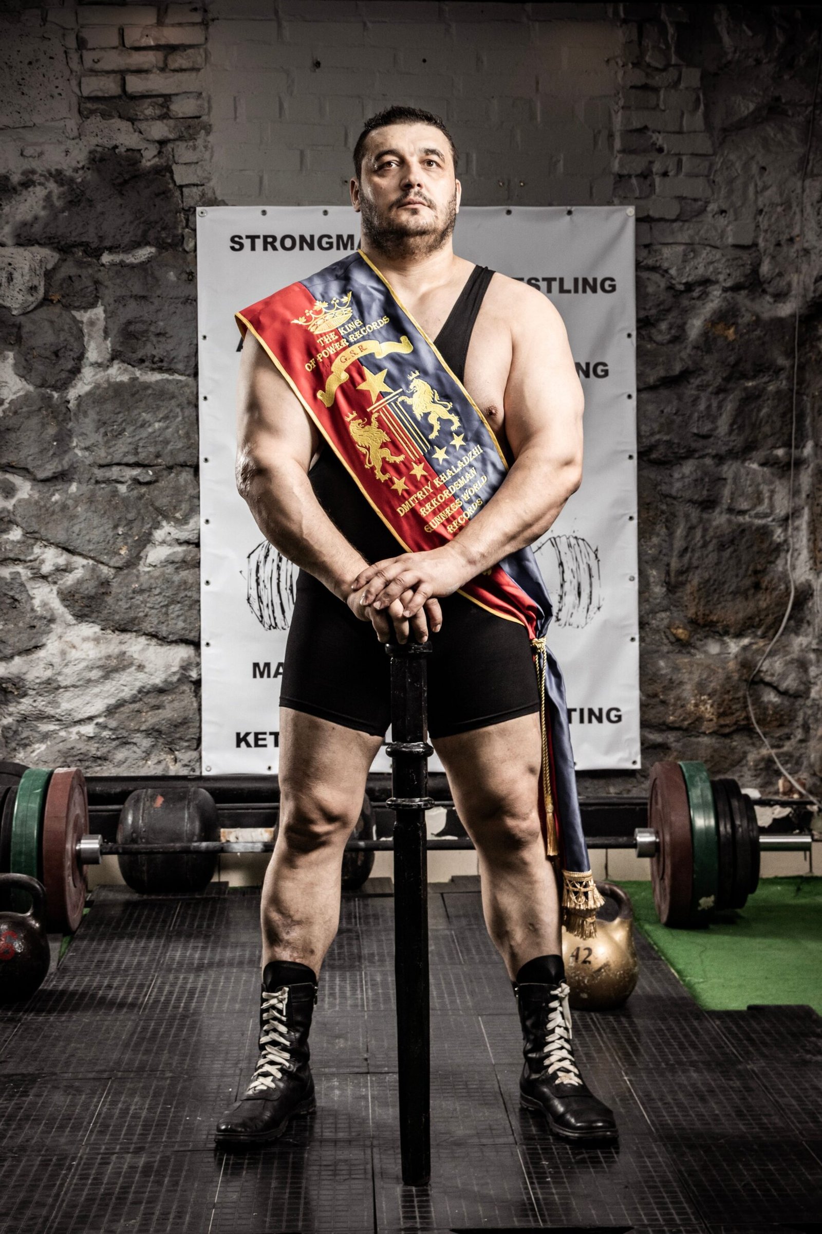 Strongman athlete standing in a training gym beside heavy weights