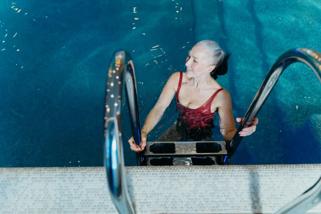 Older woman smiling beside an indoor swimming pool