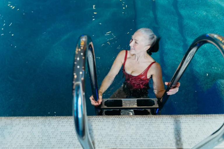 Older woman smiling beside an indoor swimming pool