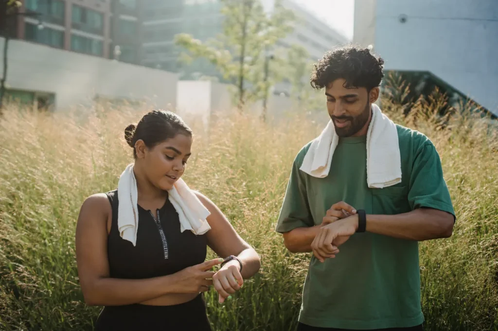 Two people checking fitness watches after an outdoor workout