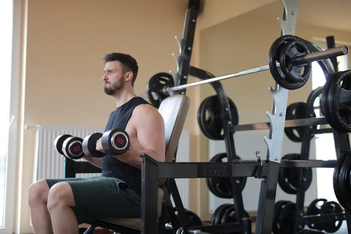 Man performing dumbbell strength training in a gym