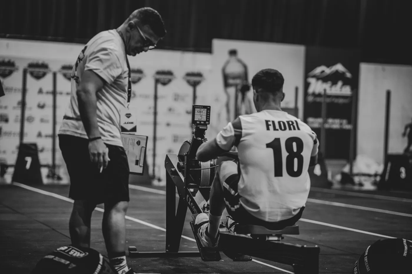Athlete rowing indoors with coaching nearby