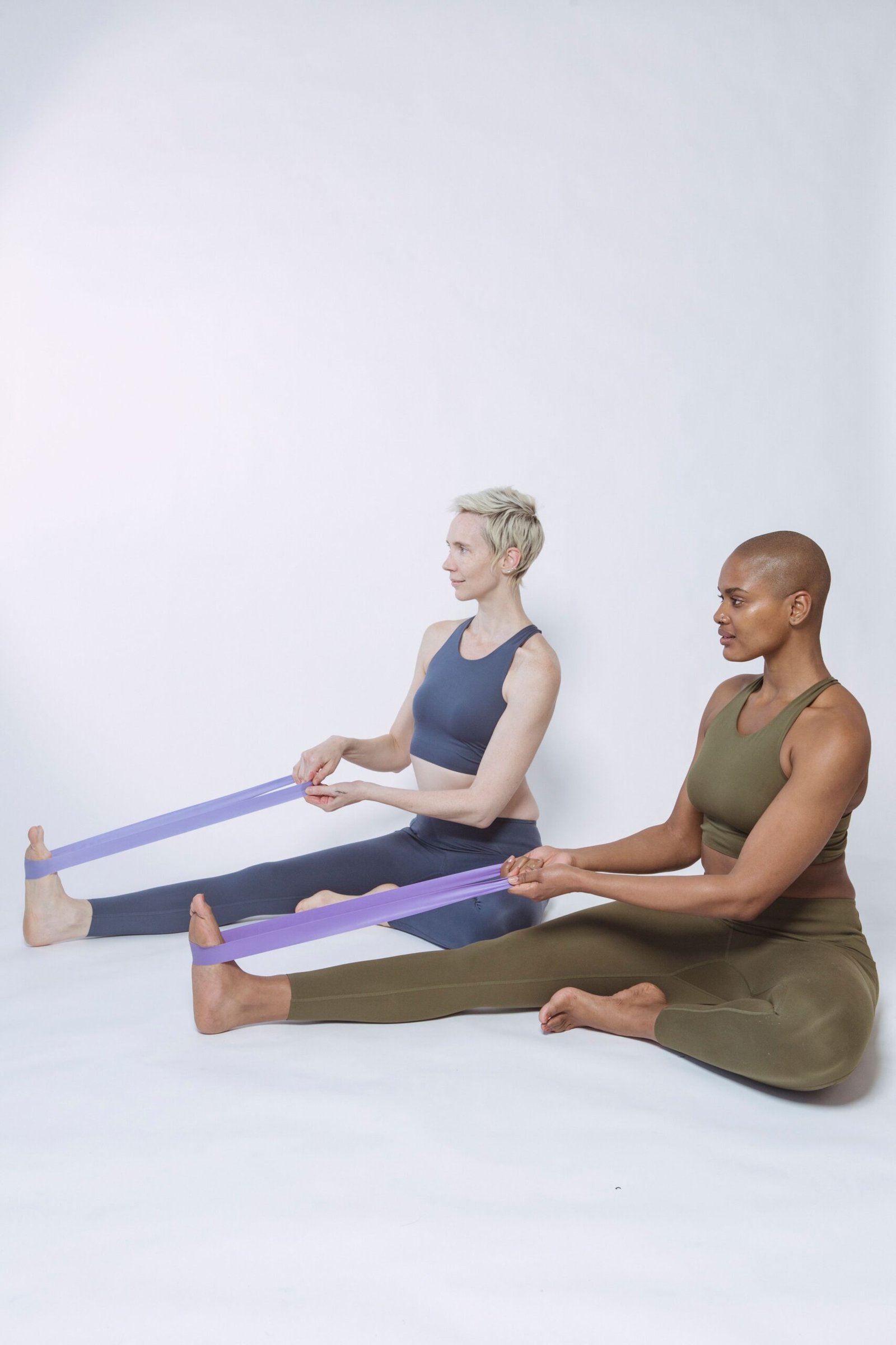 Two athletes using resistance bands while seated on the floor