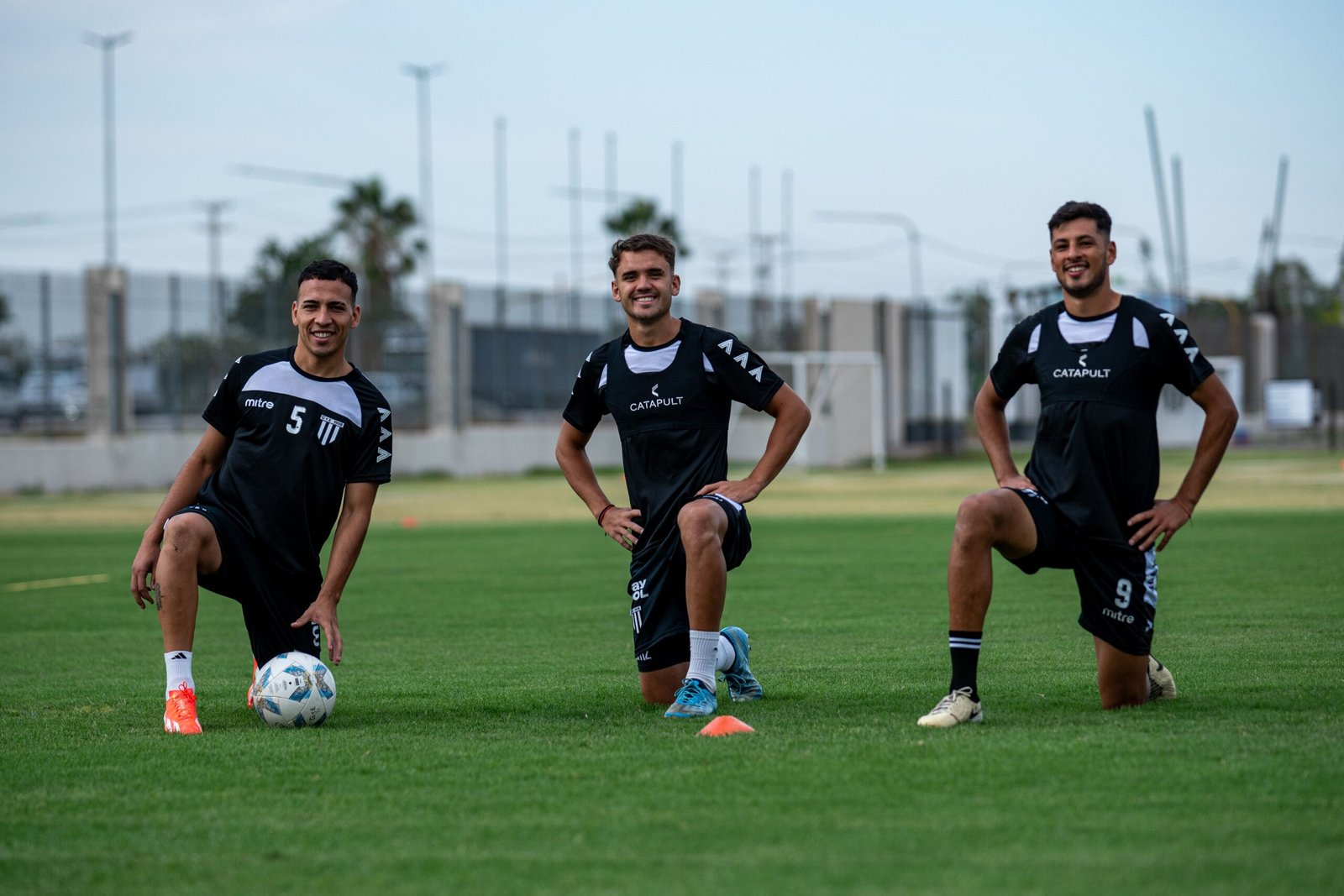 Three football players preparing with kneeling warm-up movements