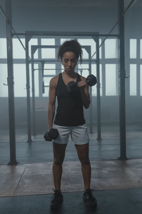 Woman completing a controlled dumbbell curl in a gym