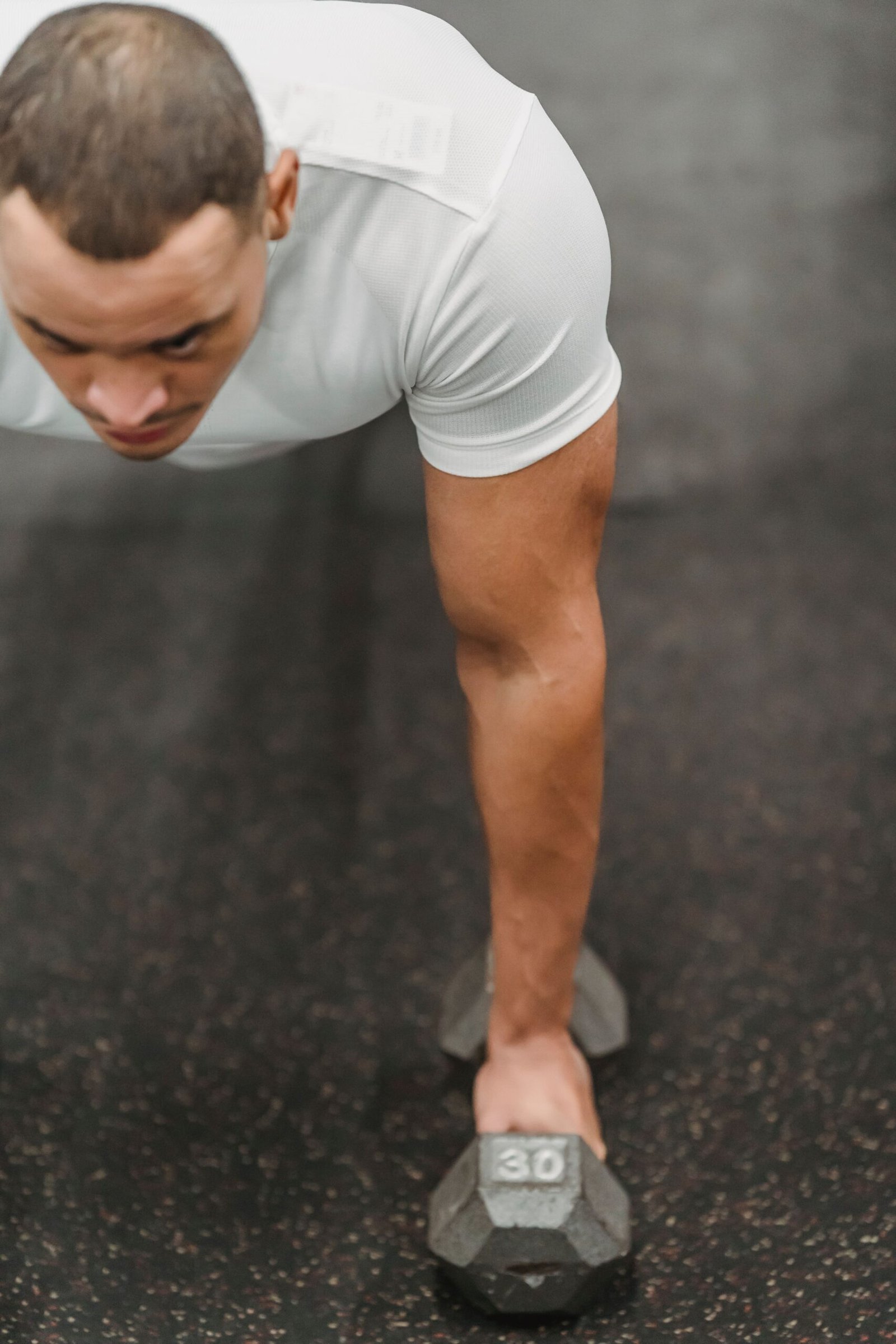 Man bracing through a dumbbell-supported plank in a gym