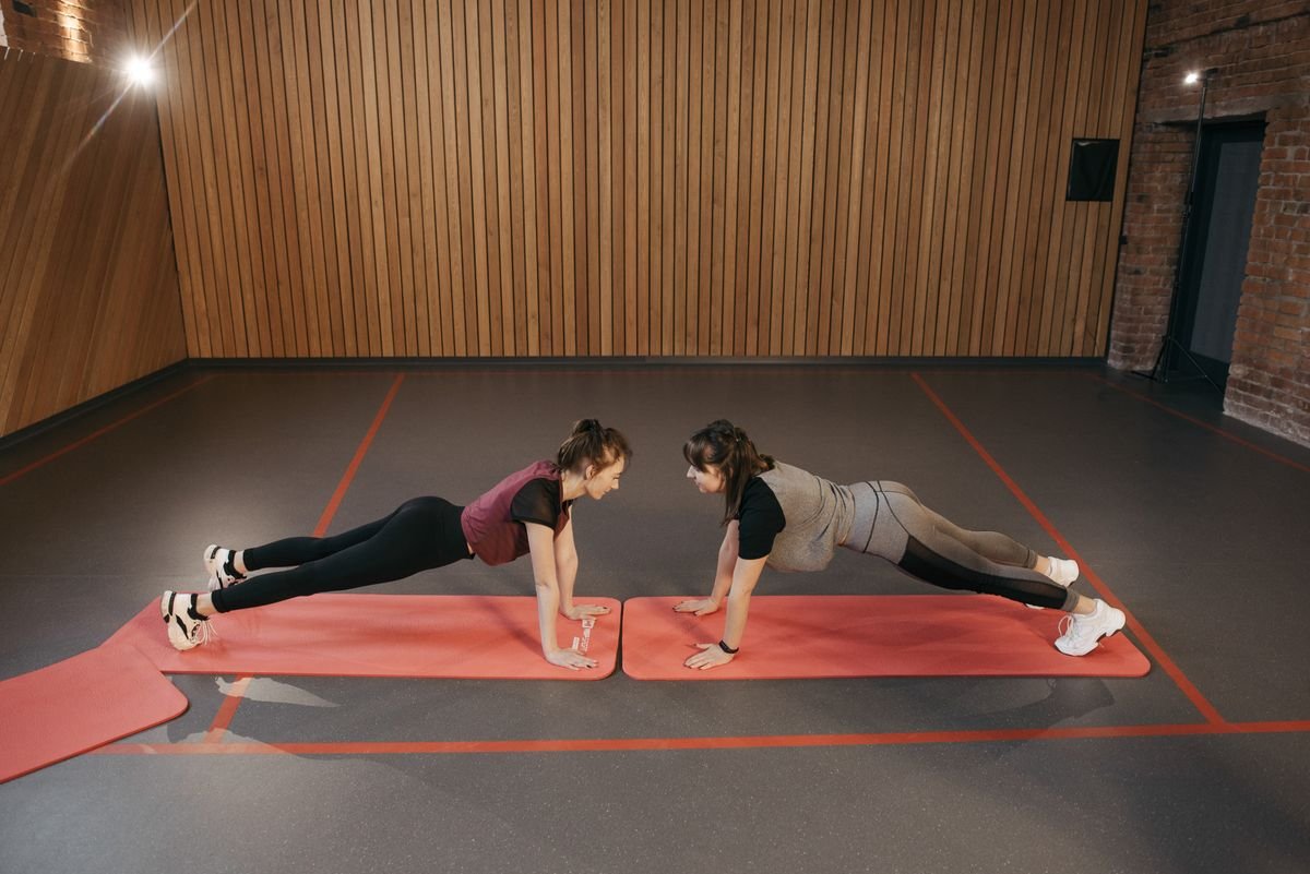 Two women performing static plank holds on mats