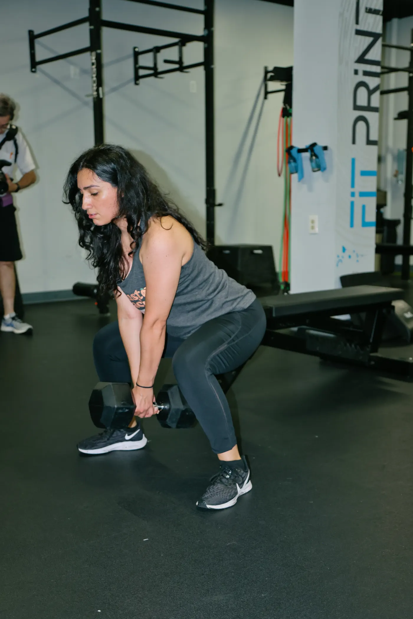 Woman performing a dumbbell hip-hinge deadlift in a gym