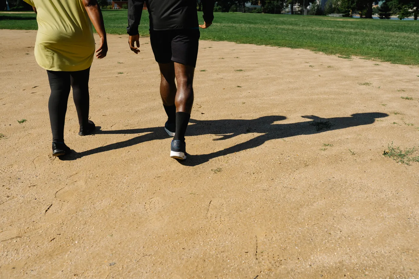 Two people walking together on a sunny park path after a meal